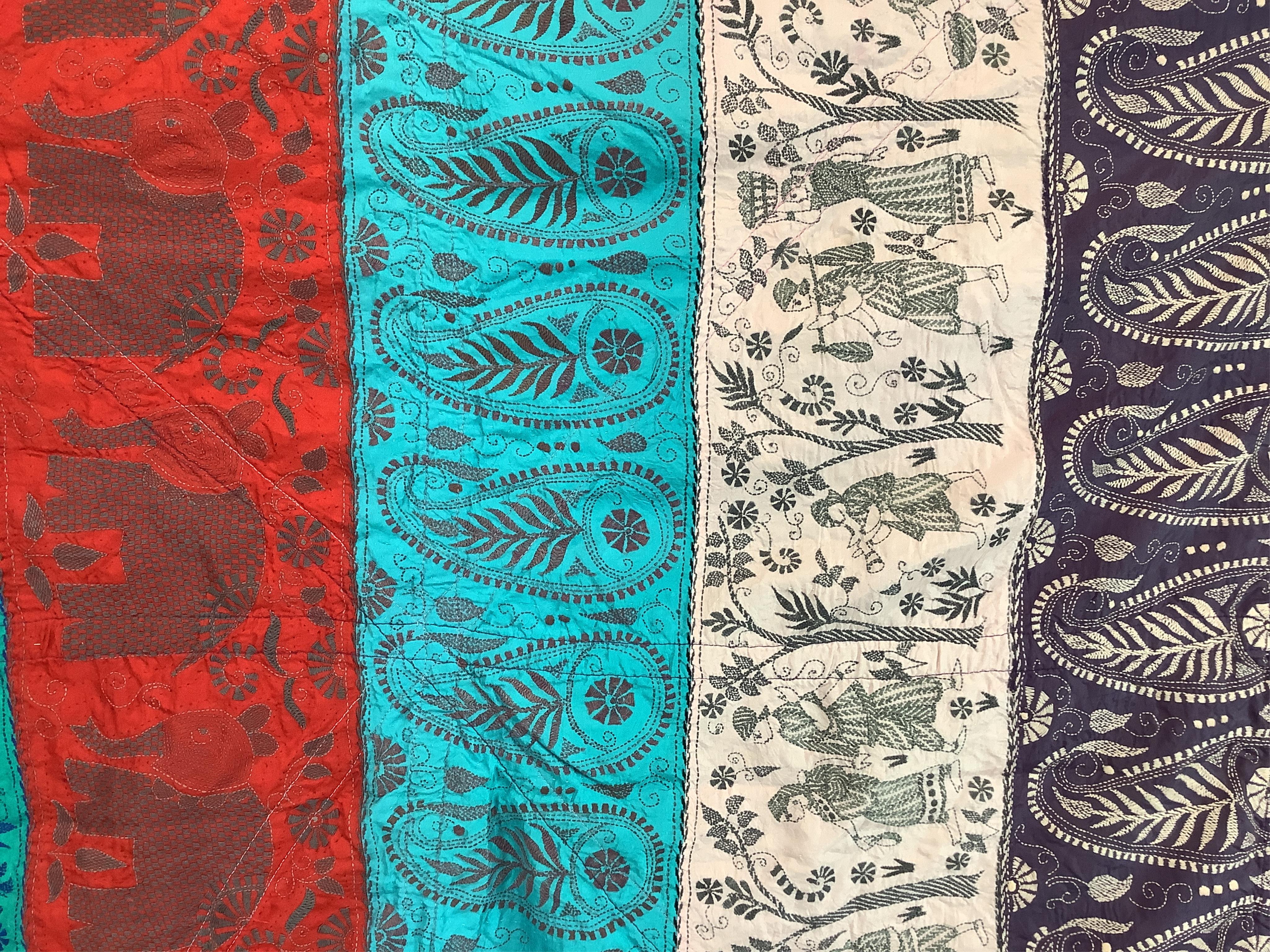 An Indian 20th century embroidered silk hanging, with decorative triangular tasselled edges. Worked in colourful silk stripes, with varying silk embroidered all over motifs. Bordered with colourful silk, beaded, tasselle